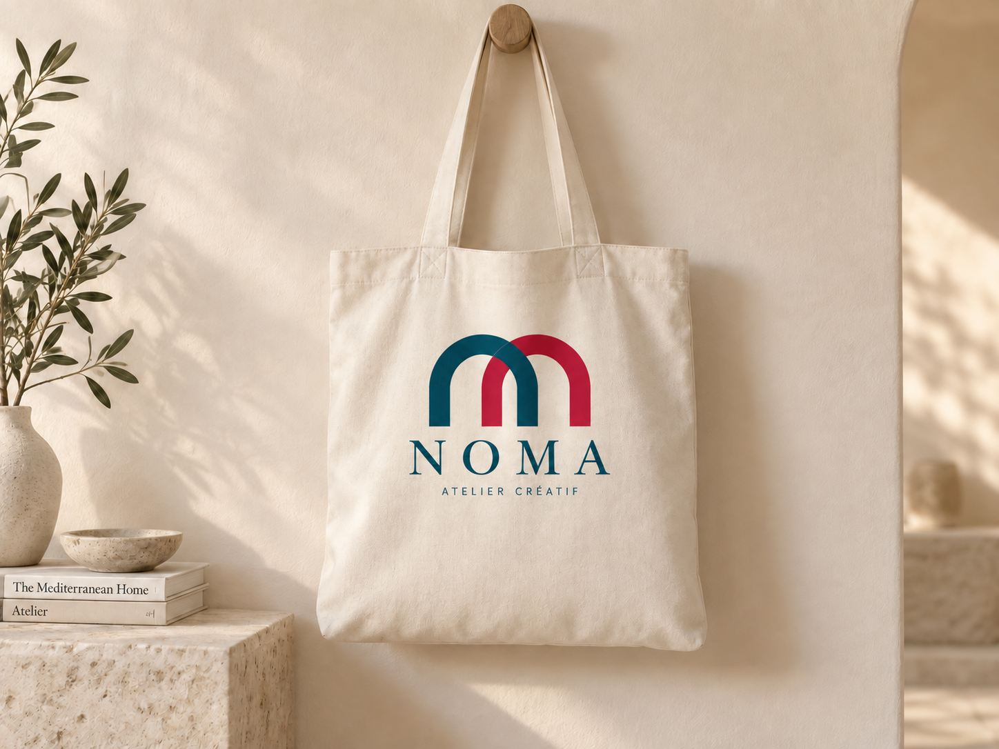 Tote bag en toile écrue imprimé d’un logo bleu et rouge, suspendu à une patère murale au-dessus d’une console