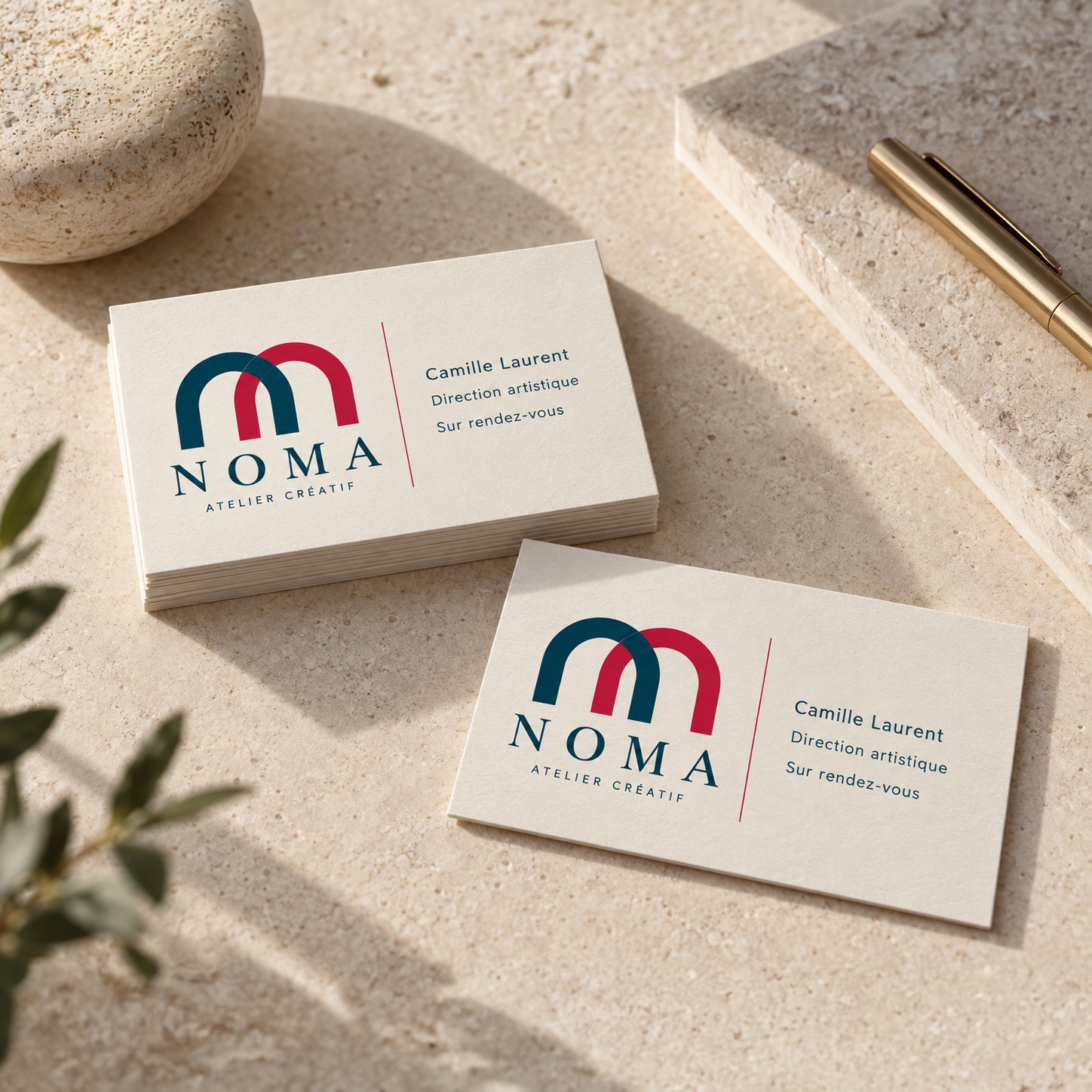 Cartes de visite recto crème avec logo, nom et fonction, une pile et une carte seule sur une surface en pierre