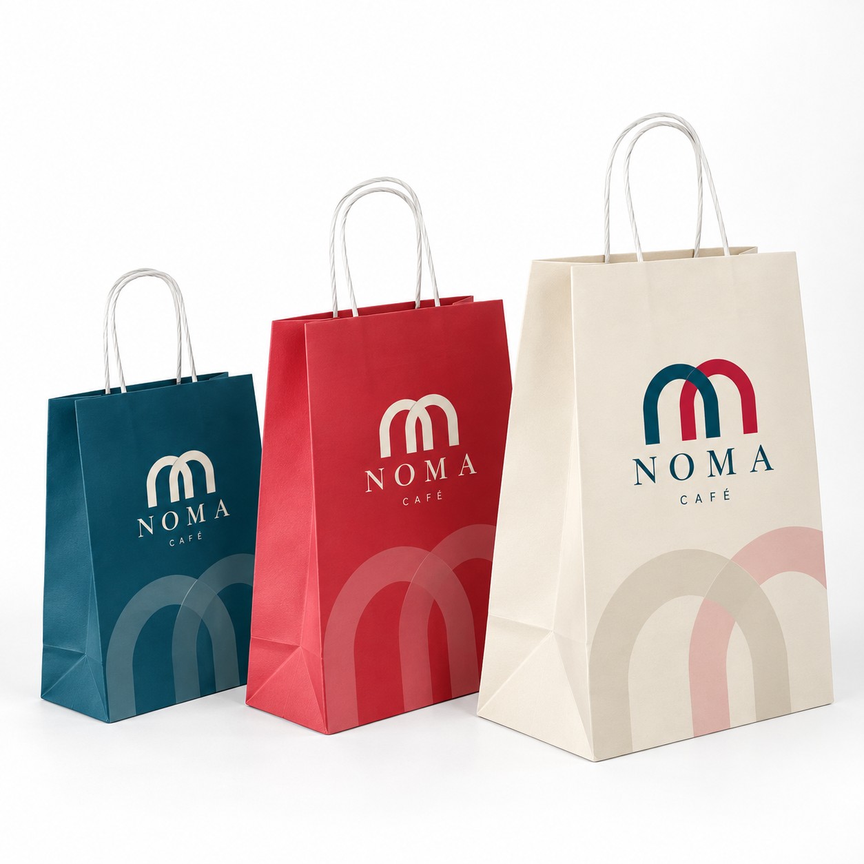 Trois sacs en papier bleu, rouge et crème à anses torsadées, imprimés au logo d'un café